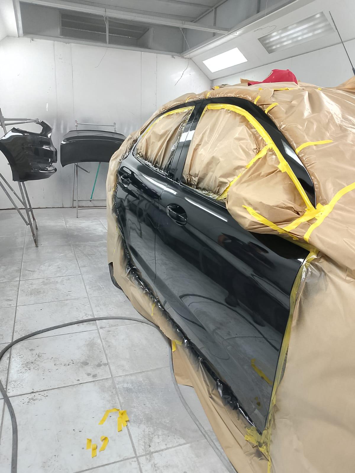 Veículo preto protegido na cabine de pintura