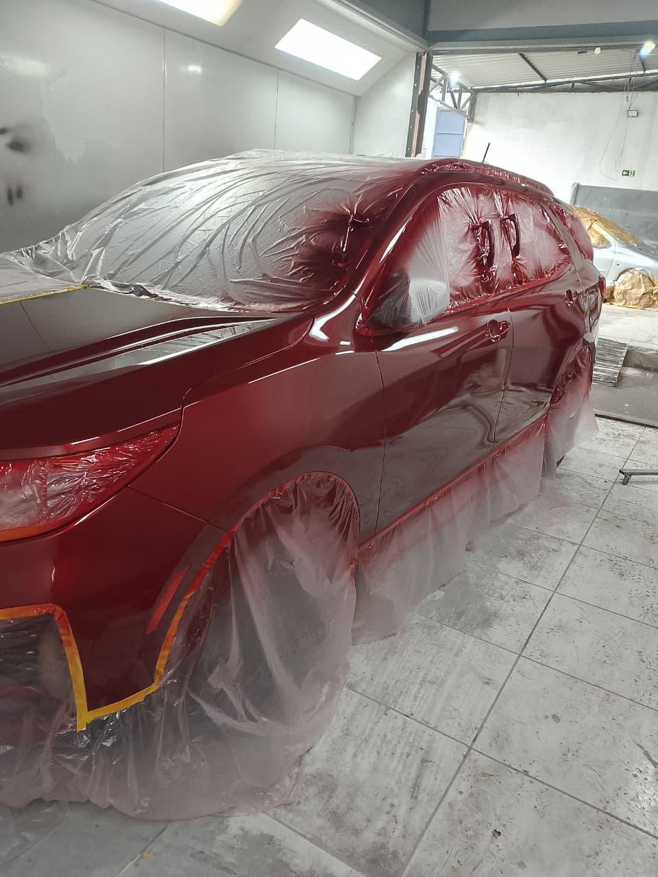 Carro vermelho em processo de pintura na oficina
